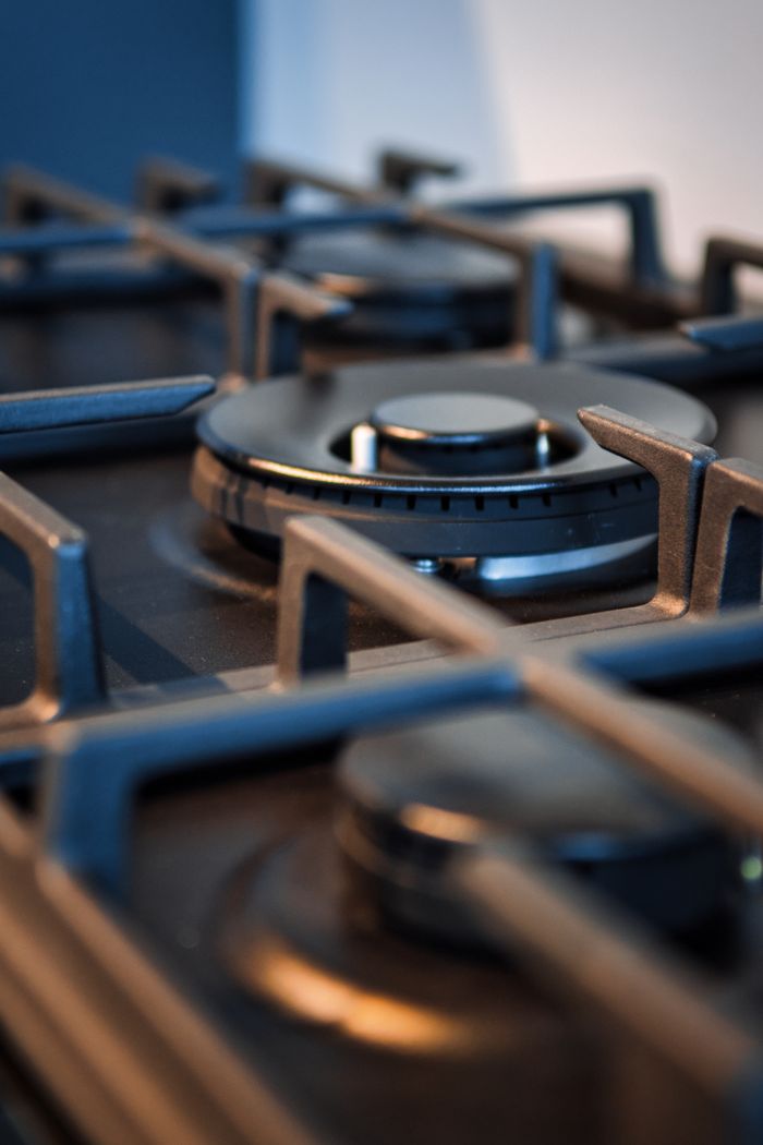 Detailed view of a modern gas stove burner with metal grates, ideal for kitchen themes.