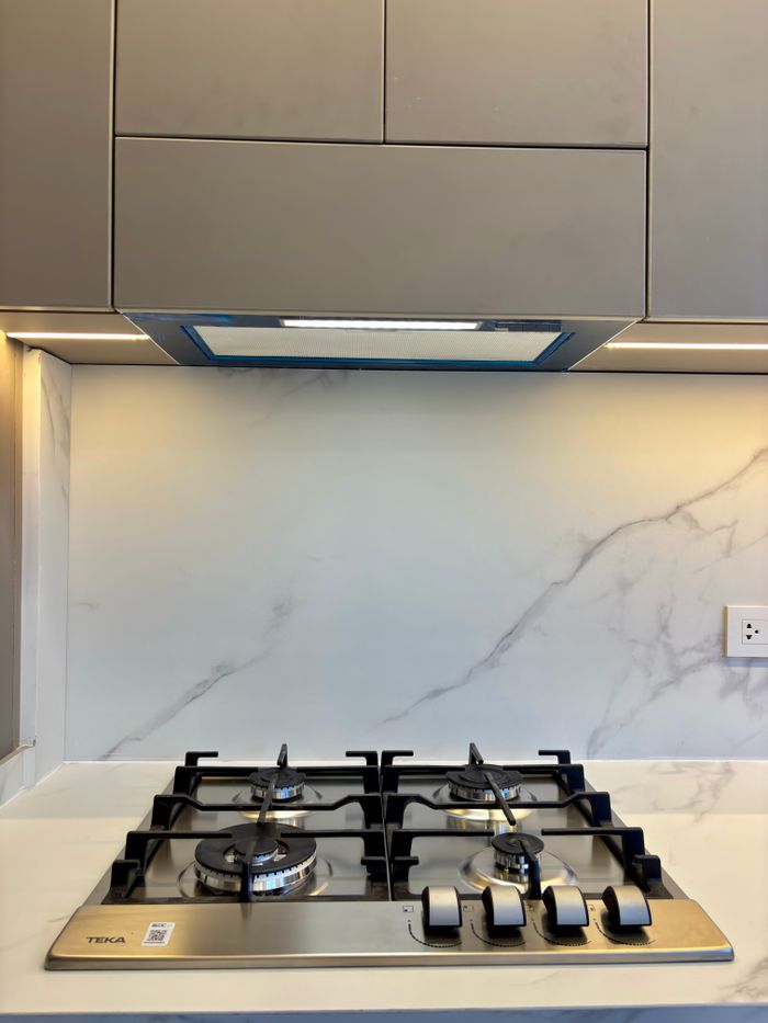 A sleek gas stove with a marble backsplash in a modern kitchen setting.